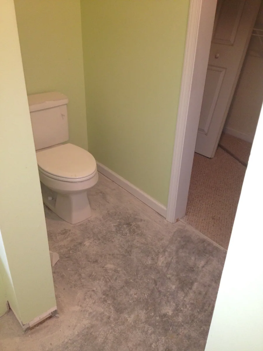 Bathroom before wall and fixture work with toilet and flooring visible