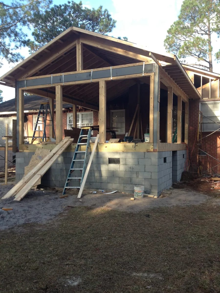 Addition wall framing above a masonry base beside a brick home