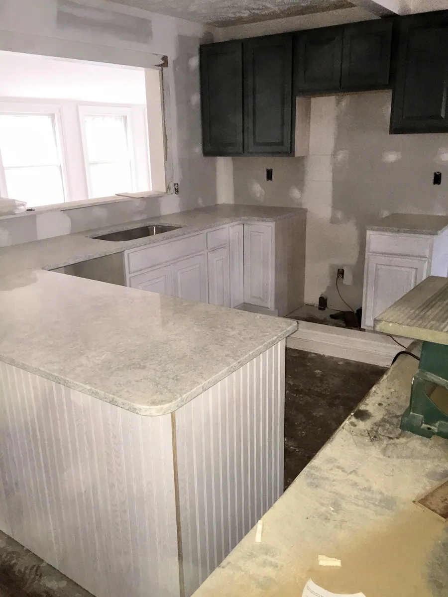Kitchen installation with upper cabinets and countertop work underway
