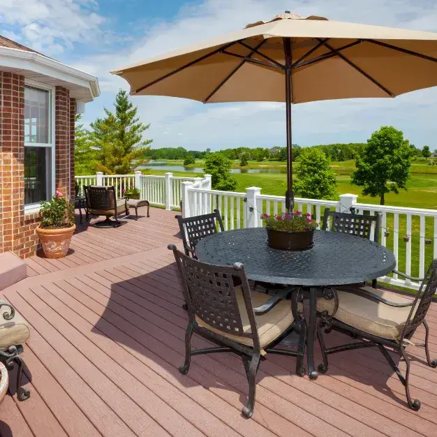 Beautiful composite deck with outdoor dining furniture and umbrella overlooking scenic golf course - premium deck building Wilmington NC by Swanson Construction
